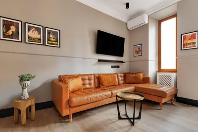 a living room with a brown leather couch and a tv at ROME City Center Apartment III in Rome