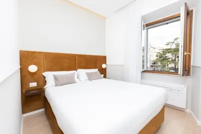 a white bedroom with a large bed and a window at Vatican Colors Rooms in Rome
