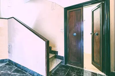an empty hallway with a wooden door and stairs at B&F Home Vatican Stay in Rome