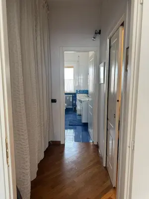 a hallway leading to a bathroom with white walls and wood floors at Attico Balduina in Rome