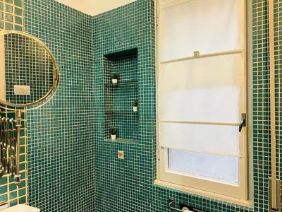 a green tiled bathroom with a shower and a window at La Porta del Perugino - near the Vatican in Rome