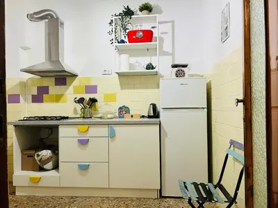 a small kitchen with a white refrigerator in it at La Porta del Perugino - near the Vatican in Rome