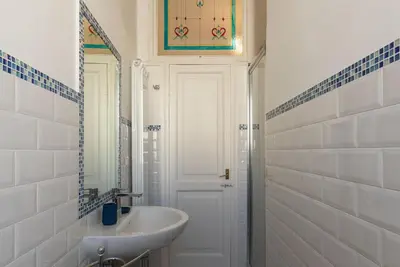 a white bathroom with a sink and a door at GuestHost - San Lorenzo Bright Apartment X8 in Rome