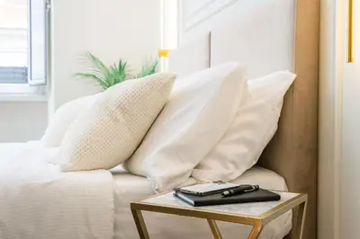 a white bed with white pillows and a table at IV Leoni in Rome