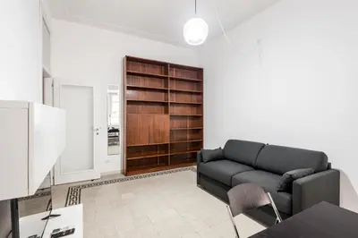 a living room with a couch and a book shelf at iFlat Mid-Century Modern Vatican Apartment in Rome