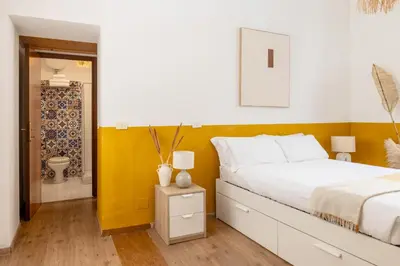 a bedroom with a white bed and a yellow accent wall at Botanico 24 Apt - Homkeey Apartments in Rome
