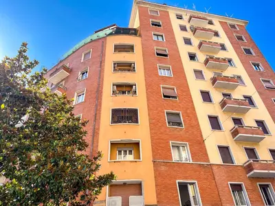 a tall brick building with windows and a tree at La Casa di Livietta in Rome