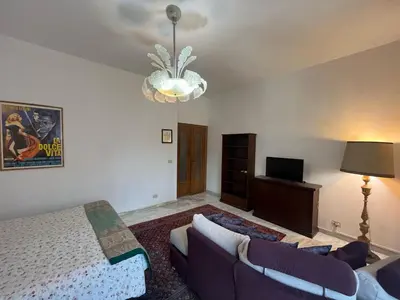 a bedroom with a bed and a couch and a chandelier at corte degli ulivi in roma in Rome