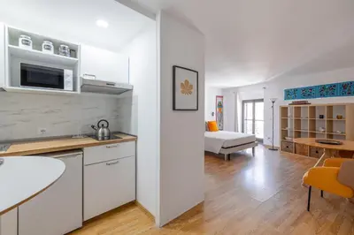 a kitchen with white cabinets and a living room at Romantic Refuge in Piazza Navona in Rome