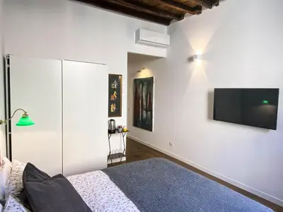 a bedroom with a bed and a flat screen tv on the wall at Roman Forum Rooms in Rome