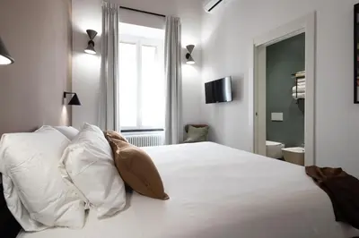 a bedroom with a white bed with pillows and a window at Style & Stone Guest House in Rome