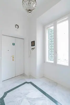 a white room with a chandelier and a door at Hermès Apartment Rome in Rome
