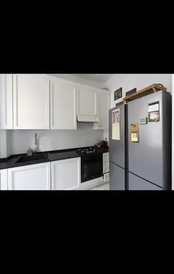 a kitchen with white cabinets and a refrigerator at Hermès Apartment Rome in Rome