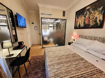 a bedroom with a large bed and a desk and a window at Venus Inn Vatican Guest House in Rome