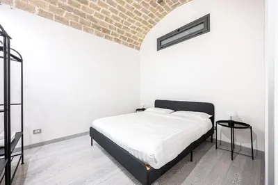 a white bedroom with a bed and a brick wall at Casa Sistina in Rome