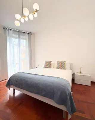 a white bedroom with a large bed and a chandelier at Casa Alice Near Vatican City - Modern, High Floor with View in Rome