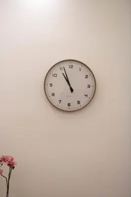 a clock on a wall with a vase of flowers at Appartamento Roma - Bredi Home in Rome