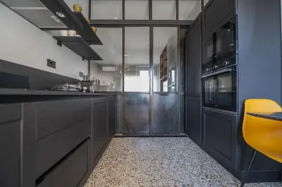 a kitchen with black cabinets and a yellow chair at Terrace Apartment Monte del Gallo by St Peter in Rome