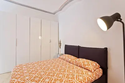 a bedroom with a bed and a lamp and white walls at Roma Pizza & Mandolino in Rome