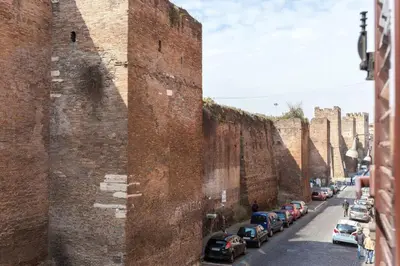 a row of cars parked next to a brick wall at Roma Pizza & Mandolino in Rome