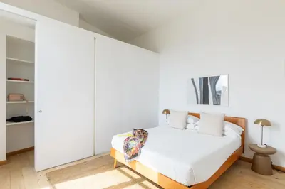 a bedroom with white walls and a bed with white sheets at iFlat Bright & Modern Living with Panoramic View in Rome