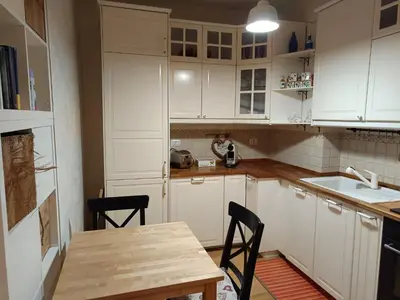 a kitchen with white cabinets and a wooden table at Alloggio turistico Artù in Rome