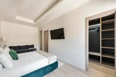 a white bedroom with a bed and a tv at Domus 28 in Rome