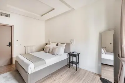 a white bedroom with a bed and a mirror at Domus 28 in Rome