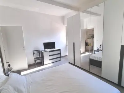 a white bedroom with a bed and a mirror at Pigneto Giardino e Posto Auto Privati in Rome