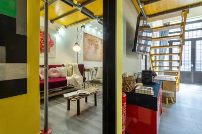 a living room with a red couch and a spiral staircase at Rossana Urban Style Loft close to Termini Station in Rome