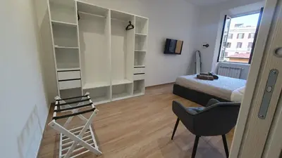 a bedroom with a bed and a chair and a window at MariElu a Trastevere in Rome