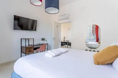 a bedroom with a white bed with a tv on the wall at iFlat Monti Brand New Spacious & Comfortable Gem in Rome