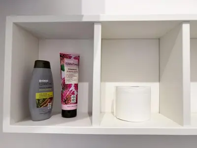 a shelf with a bottle of shampoo and a roll of toilet paper at Valerias Nest Elegant Apt with WiFi and Charm in Rome