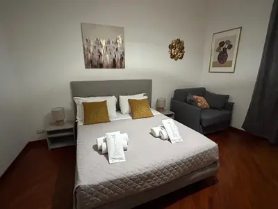 a bedroom with a large bed with a chair and a couch at Domus Vittoria in Rome
