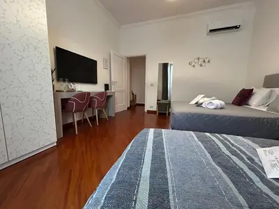 a room with two beds and a desk and a television at Domus Vittoria in Rome