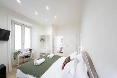 a white bedroom with a large bed and a desk at Domus Giulio Guest House in Rome