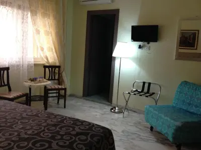 a hotel room with a bed and chairs and a television at Vatican Golden Rooms in Rome