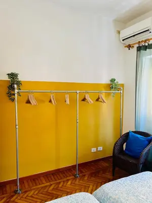 a yellow wall with hangers and a chair in a room at Trastevere vibes in Rome
