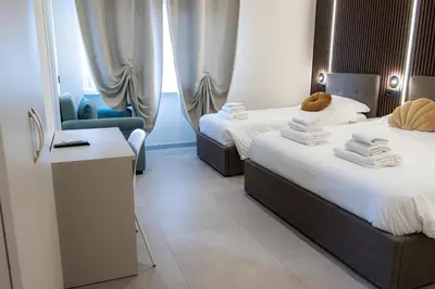 a hotel room with two beds and a chair at Luma Rooms in Rome