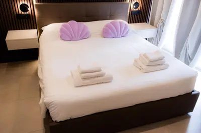 a white bed with pink pillows and towels on it at Luma Rooms in Rome