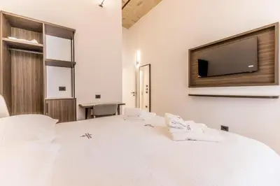 a bedroom with a large white bed with a flat screen tv at Domina Livia Vaticano Roma - Suite e Room in Rome