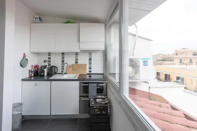 a kitchen with white cabinets and a balcony at Attic Candia - Vatican Museum in Rome
