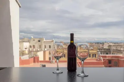 a bottle of wine and two wine glasses on a table at Attic Candia - Vatican Museum in Rome