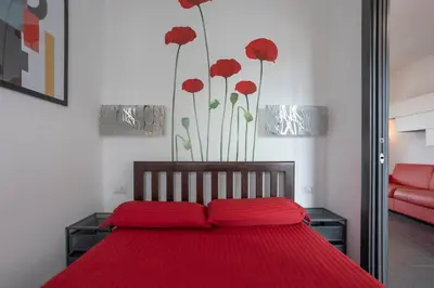 a bedroom with a bed with red sheets and red flowers on the wall at Attic Candia - Vatican Museum in Rome