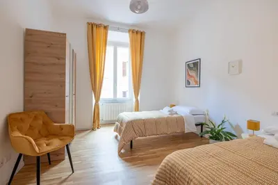a bedroom with two beds and a chair and a window at NOSTROMONDO San Cosimato Trastevere Place in Rome