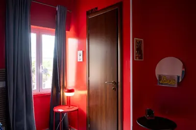 a red room with a door and a stool and a window at Sanlorenzo MaDa House in Rome
