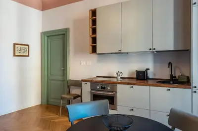 a kitchen with white cabinets and a table with blue chairs at GuestHost - Rione Prati Apartments in Rome