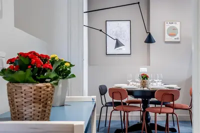 a dining room with a table and chairs and a vase with flowers at Flowers Apartment - grande casa a Montesacro in Rome