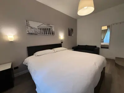 a bedroom with a large white bed and a couch at Rome Inn Vatican View Rooms in Rome