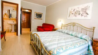 a bedroom with a bed and a red chair at B&B La Perla di Roma in Rome